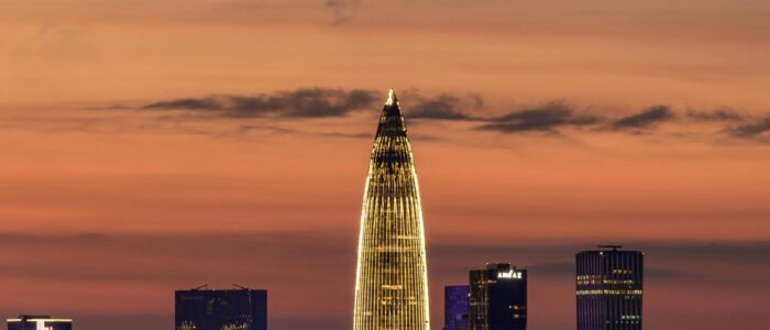 Illuminated city skyline featuring a distinct tall building at sunset.