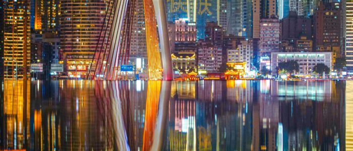 Stunning night view of Chongqing's futuristic skyline with vibrant neon lights reflecting on the river.